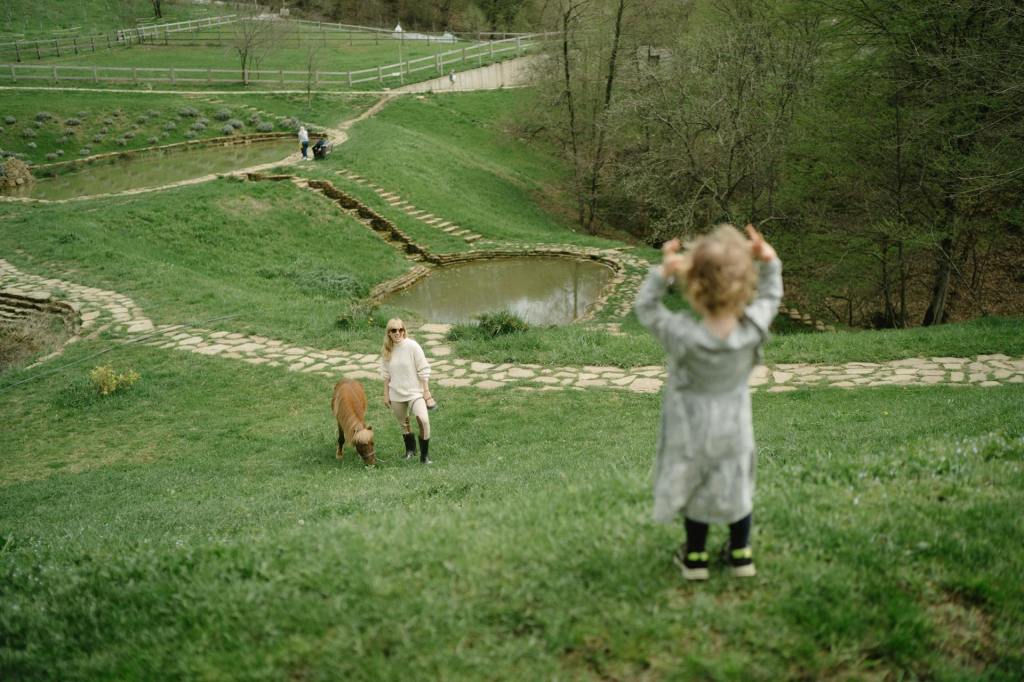 Mother walking a pony whilst looking up to her child
